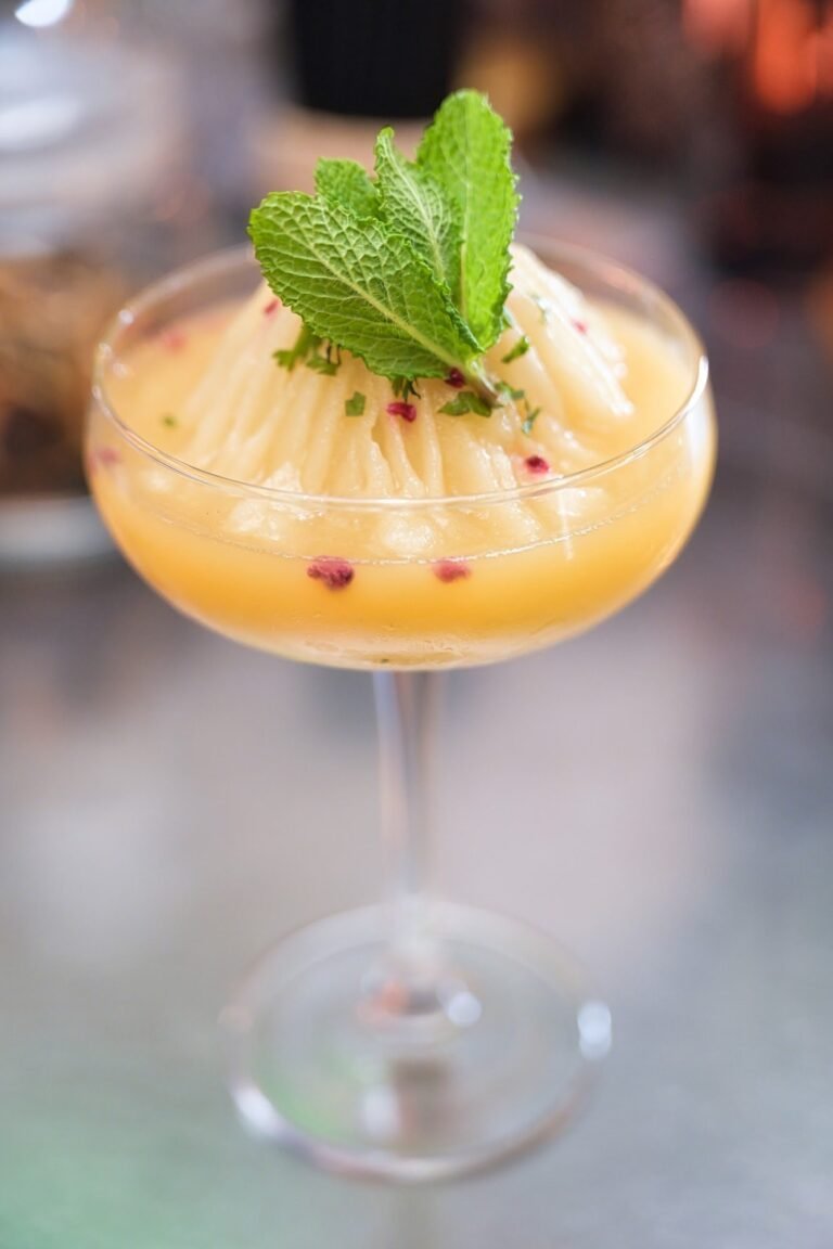 A frozen mango cocktail topped with fresh mint