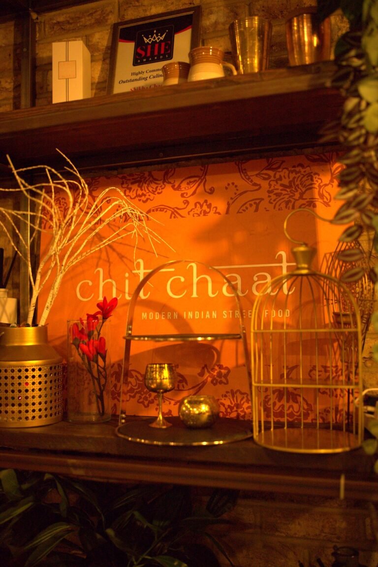 The Chit Chaat logo wall with brass lanterns and flowers