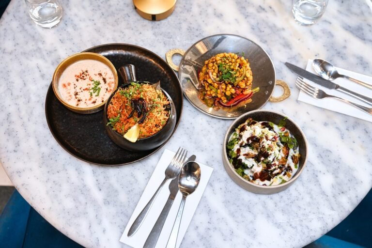 A table of sharing dishes from above: biryani, raita, chaat and kebabs